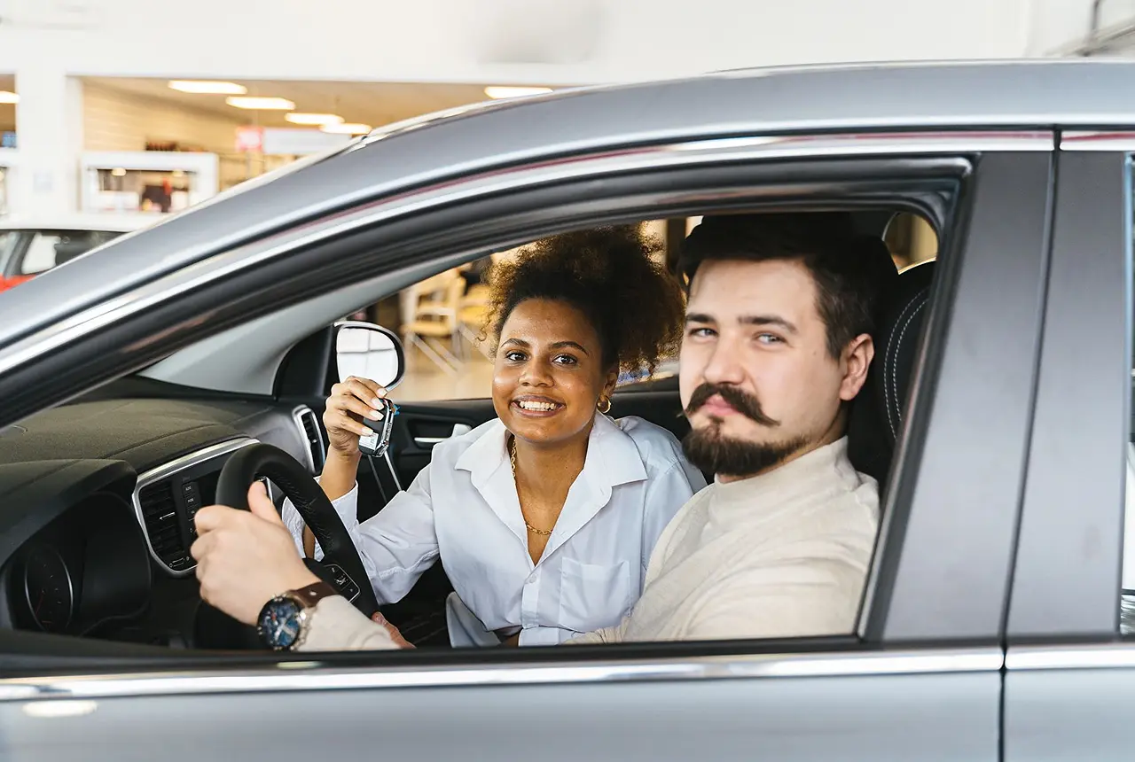 Diverses Paar glücklich in einem neuen Elektroauto